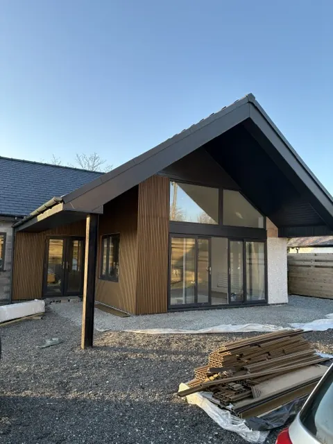 New build with a steep gable, full-height glazing and vertical timber-effect cladding. One of our jobs.